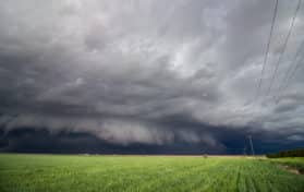 A low shelf cloud and severe storm rapidly approaches over farm country.