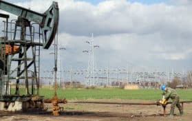 oil field with pump jack and worker