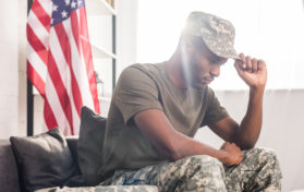 African american soldier in camouflage clothes sitting on sofa