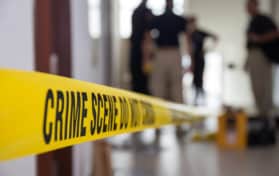 crime scene tape in building with blurred forensic team background